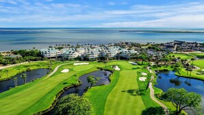 A golf course with a large clubhouse, a pond, and a view of the ocean. - PERFECT 2BR Seabrook Getaway, Pool Access, Golf View, One Block to Beach & Club! (Seabrook Island)