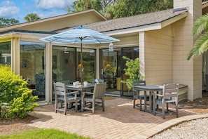 A patio with a glass enclosure, outdoor furniture, and a view of the surrounding greenery.