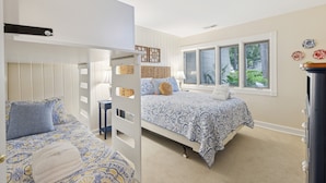 A bedroom with two beds, a window with blinds, a bedside table, and a decorative wall piece. - 56 Woodbine Villa @ Sea Pines | Walk to Beach Club| Golf View | Pickleball & Tennis (Hilton Head Island)