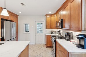 A modern kitchen with wooden cabinets, stainless steel appliances, and a white countertop. - Ground Floor Sea Pines Villa w/ Lagoon & Golf Views, Near Sea Pines Beach Club (Hilton Head Island)