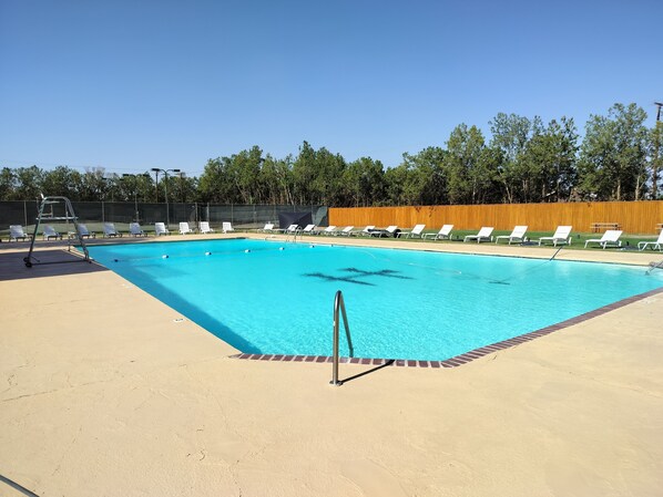 A swimming pool with white lounge chairs and a wooden fence in the background. - Peaceful Retreat near Texas Tech with Epic Game room! (Lubbock)