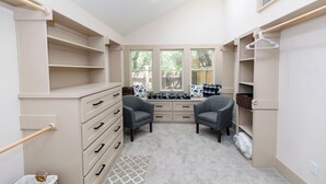 A walk-in closet with open shelves, a bench, and a hanging rack. - Peaceful Retreat near Texas Tech with Epic Game room! (Lubbock)
