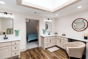A modern bathroom with a skylight, a large mirror, a sink, and a vanity. - Peaceful Retreat near Texas Tech with Epic Game room! (Lubbock)