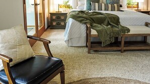 Une chambre à coucher avec un lit, une chaise, un ventilateur de plafond et un tableau accroché au mur.