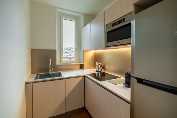 A modern kitchen with a built-in oven, a kettle, and a refrigerator.