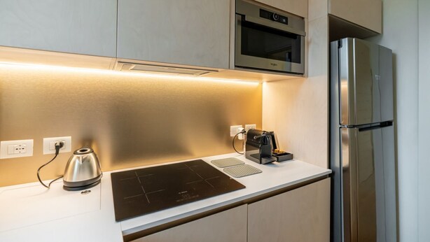 A modern kitchen with a built-in oven, a stainless steel refrigerator, and a black induction cooktop.