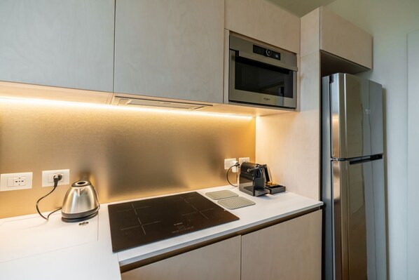 Una cocina moderna con horno integrado, refrigerador de acero inoxidable y placa de inducción negra.