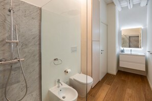 A bathroom with a shower, toilet, sink, and a mirror above the sink.