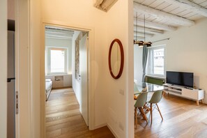 Un espacio habitable moderno con comedor, televisor y cocina al fondo.