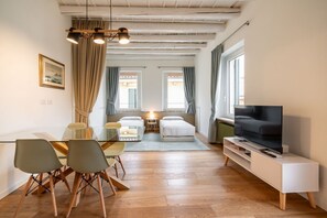 Una sala moderna con comedor, televisor y dos ventanas con cortinas.