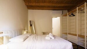 A bedroom with a bed, a chair, a wardrobe, and a mirror.