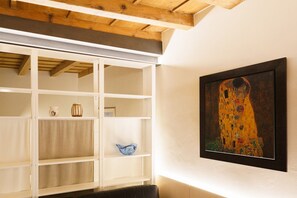 A room with a white shelving unit, a framed painting, and a wooden ceiling. - Modern residence with balconies overlooking Piazza Erbe (Verona)