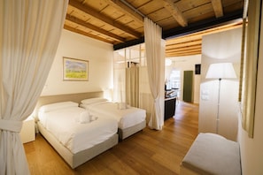 A hotel room with two beds, a wooden ceiling, a painting on the wall, and a lamp. - Modern residence with balconies overlooking Piazza Erbe (Verona)