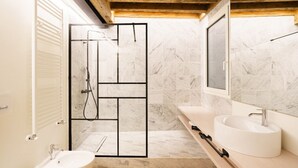 A modern bathroom with a shower enclosure, a sink, and a bidet.