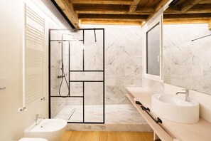 A modern bathroom with a shower enclosure, a sink, and a bidet. - Modern residence with balconies overlooking Piazza Erbe (Verona)