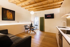 A modern kitchen with a wooden ceiling, a dining area with a table and chairs, a black sofa, and a framed painting on the wall. - Modern residence with balconies overlooking Piazza Erbe (Verona)