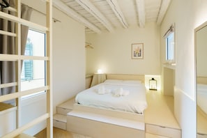 A bedroom with a bed, bedside tables, a nightstand, a window with curtains, a wall-mounted picture, and a ceiling with exposed beams. - Modern residence with balconies overlooking Piazza Erbe (Verona)
