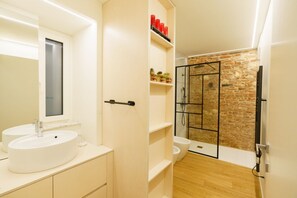 A bathroom with two sinks, a glass shower enclosure, and a brick wall. - Modern residence with balconies overlooking Piazza Erbe (Verona)