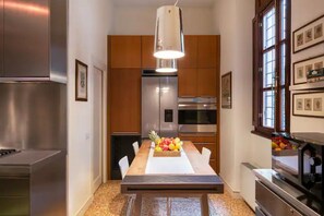 A modern kitchen with stainless steel appliances, wooden cabinets, and a central island with fruit.