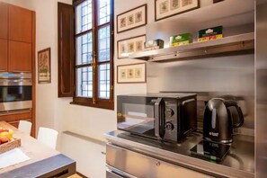 A modern kitchen with stainless steel appliances, a coffee maker, and framed pictures on the wall.