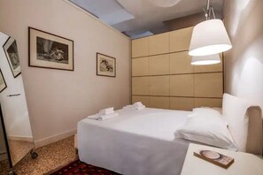 A hotel room with a bed, a bedside table, and a large window.