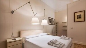 Una habitación de hotel con una cama, una mesita de noche, una lámpara y un cuadro en la pared.