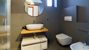 A modern bathroom with a round mirror, a vessel sink, a toilet, and a bidet. - Spacious and bright penthouse with 3 small balconies (Verona)