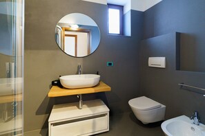 A modern bathroom with a round mirror, a vessel sink, a toilet, and a bidet. - Spacious and bright penthouse with 3 small balconies (Verona)