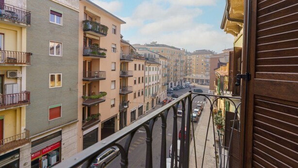 A narrow street with multi-story buildings, balconies, and a pedestrian walkway. - Spacious and bright penthouse with 3 small balconies (Verona)