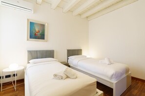 A hotel room with two beds, a painting on the wall, and an air conditioning unit. - Spacious and bright penthouse with 3 small balconies (Verona)