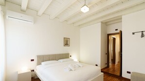 A bedroom with a bed, bedside tables, a mirror, and a door leading to another room. - Spacious and bright penthouse with 3 small balconies (Verona)