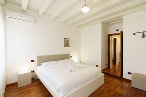 A bedroom with a bed, bedside tables, a mirror, and a door leading to another room. - Spacious and bright penthouse with 3 small balconies (Verona)