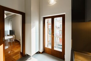 A room with a wooden door, a dining area with a table and chairs, and a view of a balcony with railings. - Spacious and bright penthouse with 3 small balconies (Verona)