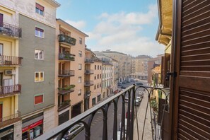 Una calle estrecha flanqueada por edificios de varios pisos, balcones y una acera para peatones.
