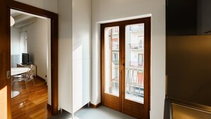 A room with a wooden door, a dining area with a table and chairs, and a view of a balcony with railings. - Spacious and bright penthouse with 3 small balconies (Verona)