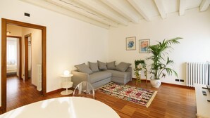 A modern living room with a sofa, a coffee table, a rug, and a potted plant. - Spacious and bright penthouse with 3 small balconies (Verona)