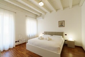 Un dormitorio con una cama, una silla, una mesita de noche y un pequeño tocador.