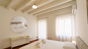 A hotel room with a large bed, a round mirror, a bedside table, and a wardrobe. - Spacious and bright penthouse with 3 small balconies (Verona)