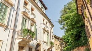 Una calle estrecha con edificios que tienen puertas de arco y contraventanas verdes.