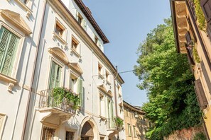 Una calle estrecha con edificios que tienen puertas de arco y contraventanas verdes.