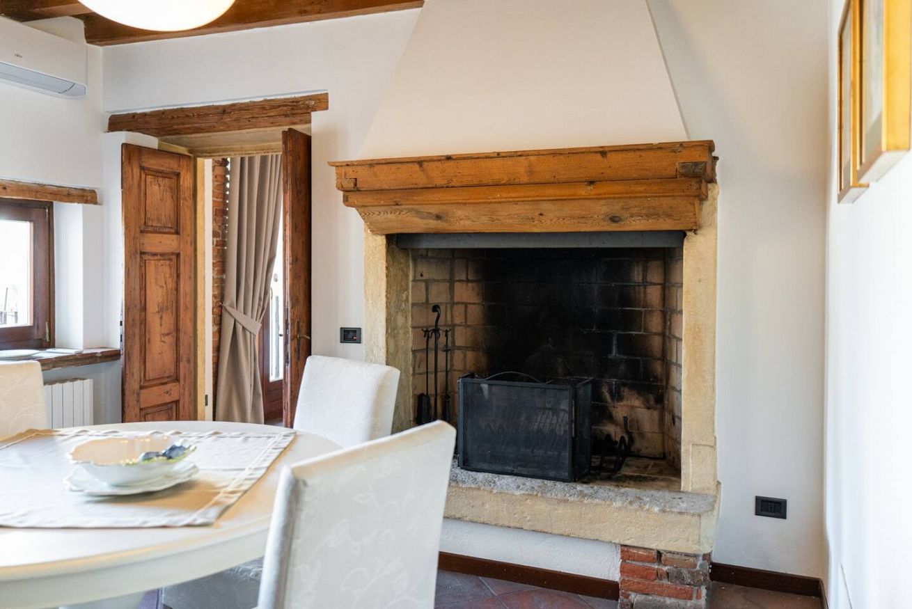 A room with a fireplace, a dining table with chairs, and a wooden door.