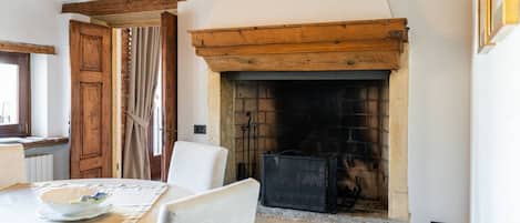 Una habitación con chimenea, una mesa de comedor con sillas y una puerta de madera.