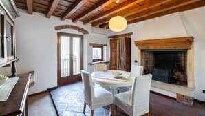 A dining area with a round table, white chairs, a hanging light fixture, and a fireplace. - Merici residence, elegant and fairytale-like (Verona)