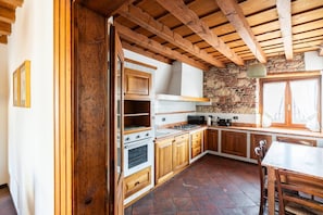 A kitchen with wooden cabinets, a stone wall, and a tiled floor. - Merici residence, elegant and fairytale-like (Verona)
