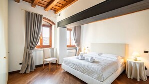 Un dormitorio con una cama grande, suelo de madera y un techo alto con vigas a la vista.
