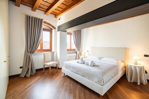 Un dormitorio con una cama grande, suelo de madera y un techo alto con vigas a la vista.