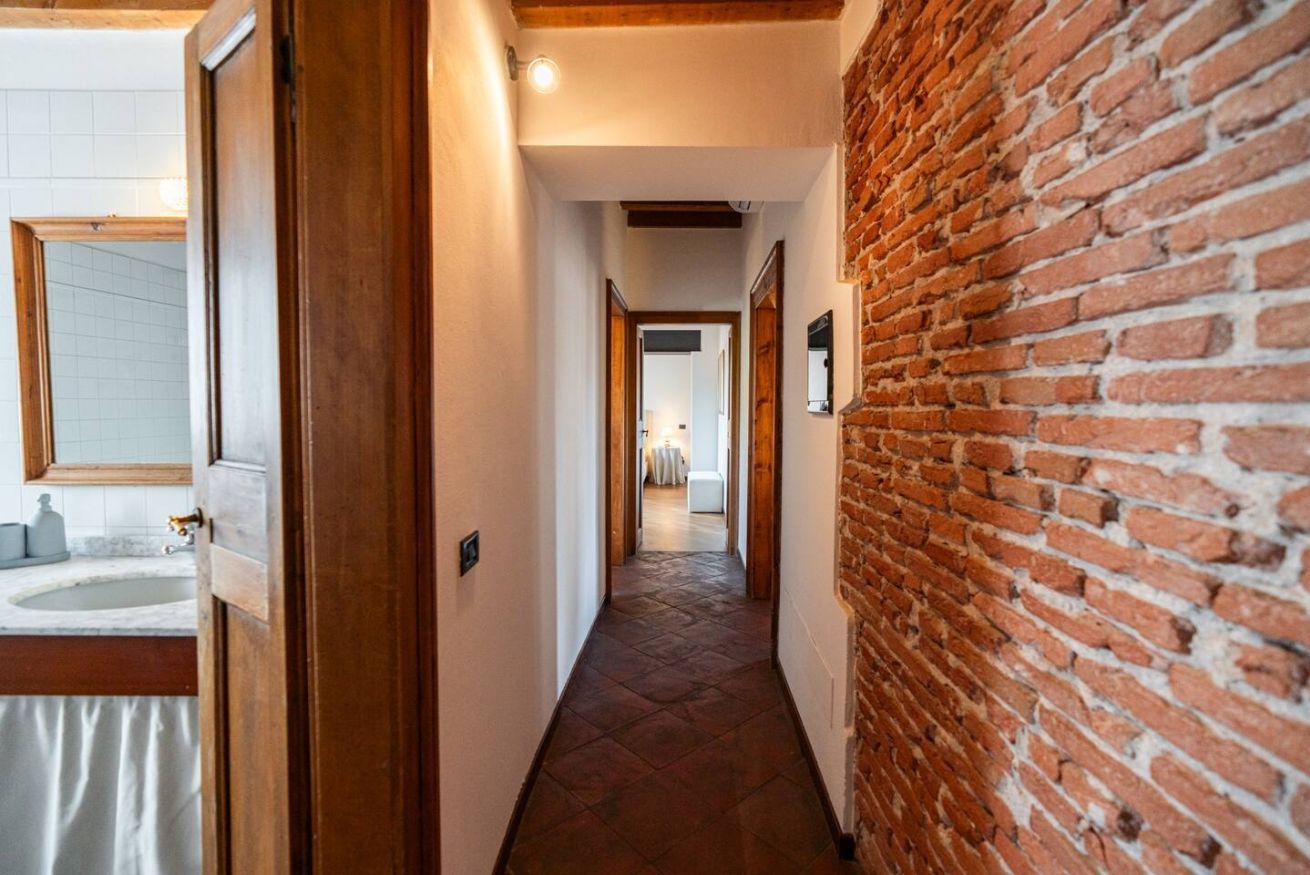 Un couloir avec un mur de briques sur la droite et une porte en bois sur la gauche.