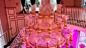 Un lustre à plusieurs niveaux orné de décorations en cristal, un escalier avec une rampe en métal et une fenêtre donnant sur un paysage verdoyant.