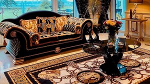 Un salon avec un canapé à motifs, une table basse et une vue sur l’extérieur grâce à de grandes fenêtres.
