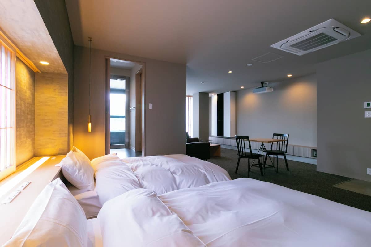 Hotellihuone, jossa on kaksi sänkyä, työpöytä ja tuoli.